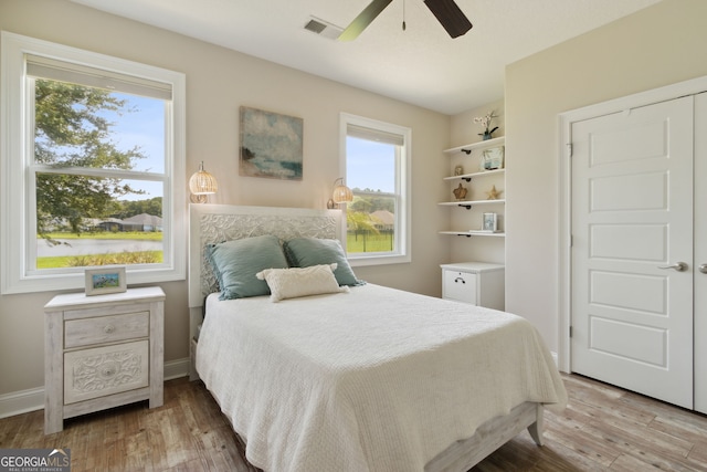 bedroom with multiple windows, wood-type flooring, and ceiling fan