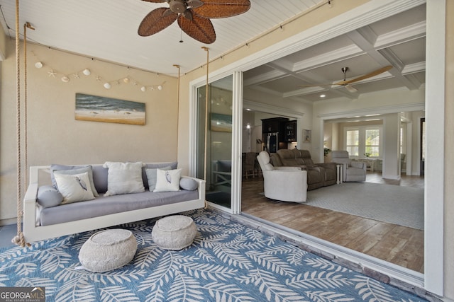 living room featuring wood-type flooring, ornamental molding, coffered ceiling, beamed ceiling, and ceiling fan