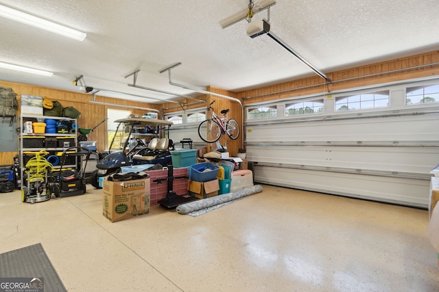 garage featuring a garage door opener and wooden walls