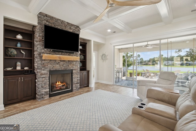 living room featuring a fireplace, light hardwood / wood-style floors, beamed ceiling, and crown molding