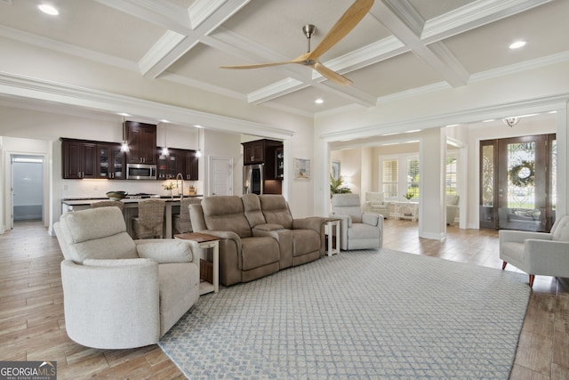 living room with ornamental molding, light hardwood / wood-style flooring, beamed ceiling, and ceiling fan