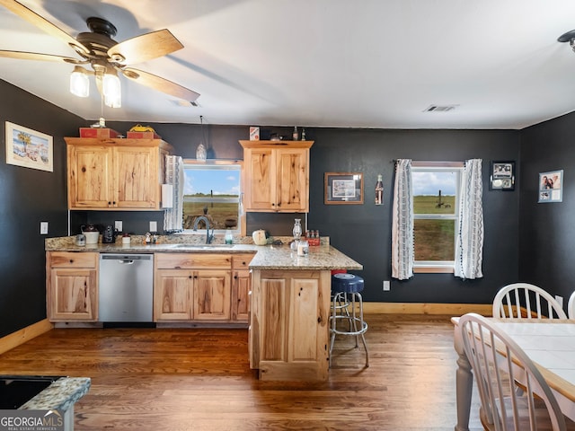 kitchen with a healthy amount of sunlight, stainless steel dishwasher, a kitchen island, and sink