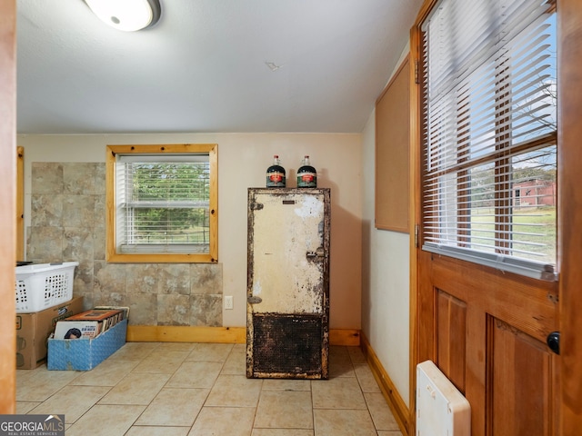 entrance foyer with light tile patterned flooring and tile walls