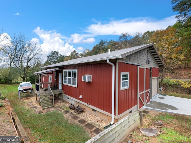 view of property exterior with a garage, an outdoor structure, and a wall mounted AC