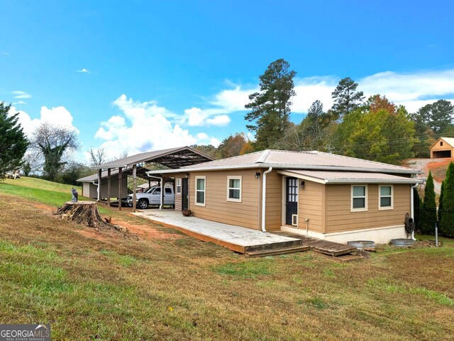 back of house featuring a carport and a lawn