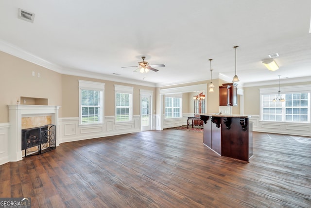 kitchen with a kitchen breakfast bar, a fireplace, crown molding, dark wood-type flooring, and pendant lighting