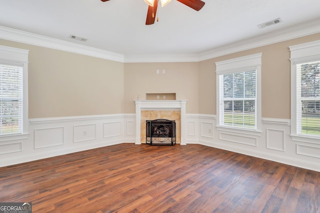 unfurnished living room with dark hardwood / wood-style flooring, a tiled fireplace, ceiling fan, and ornamental molding