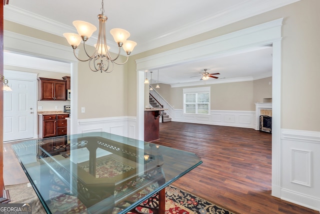 dining space featuring ceiling fan with notable chandelier, dark wood-type flooring, and crown molding