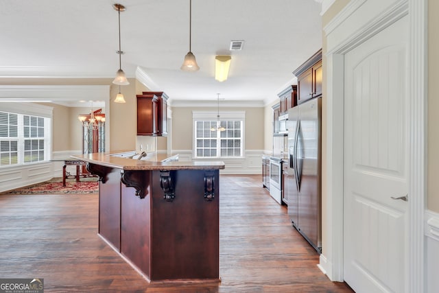 kitchen with hanging light fixtures, a kitchen bar, a healthy amount of sunlight, and stainless steel appliances