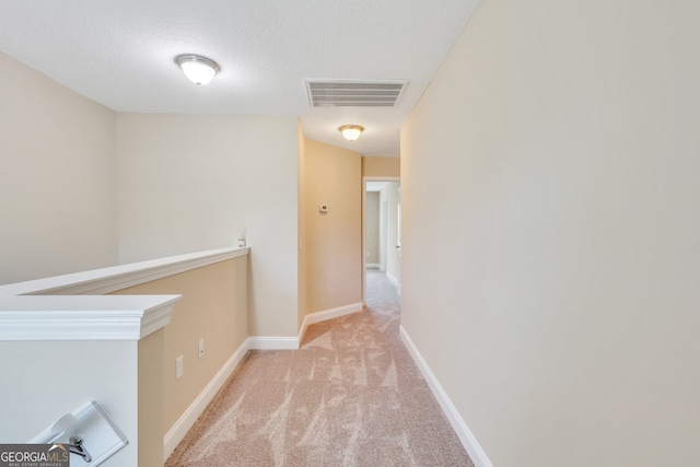 hall featuring a textured ceiling and light carpet