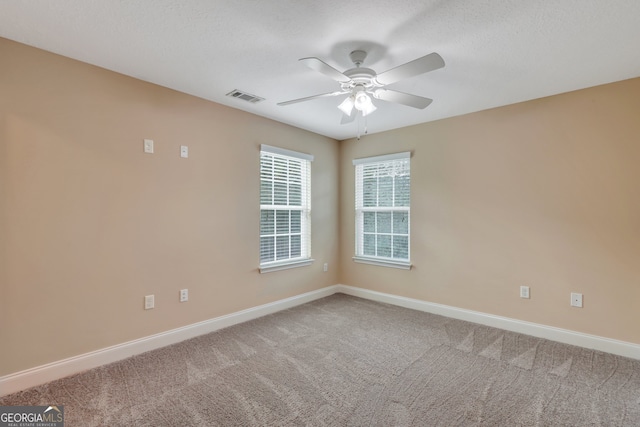 carpeted spare room featuring a textured ceiling and ceiling fan