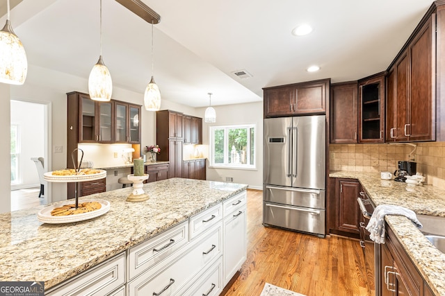 kitchen featuring white cabinets, high end refrigerator, tasteful backsplash, and light stone countertops