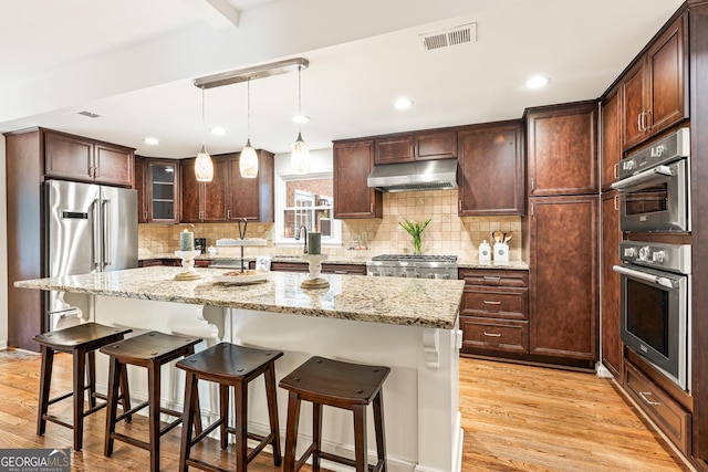 kitchen with a center island, light wood-type flooring, and light stone countertops