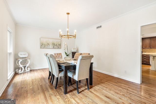 dining room featuring a chandelier, light hardwood / wood-style flooring, and ornamental molding