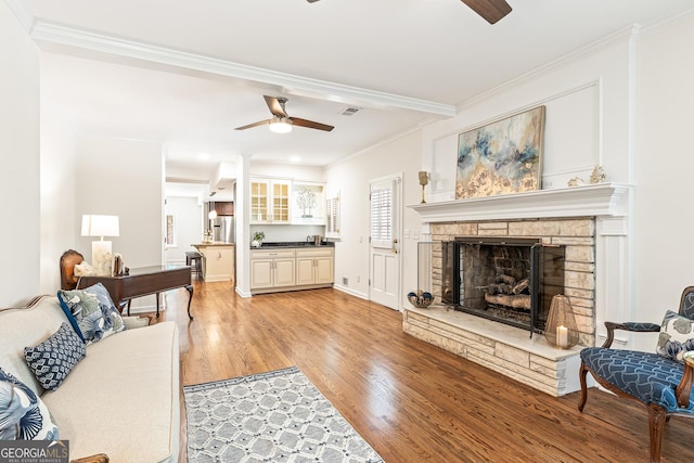 living room with a fireplace, ceiling fan, crown molding, and light hardwood / wood-style flooring