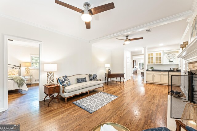 living room with ceiling fan, light wood-type flooring, and ornamental molding