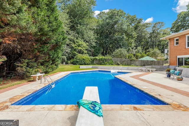 view of swimming pool featuring a patio and a diving board