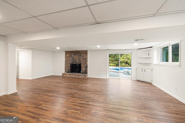 unfurnished living room featuring a fireplace, wood-type flooring, a paneled ceiling, and built in features