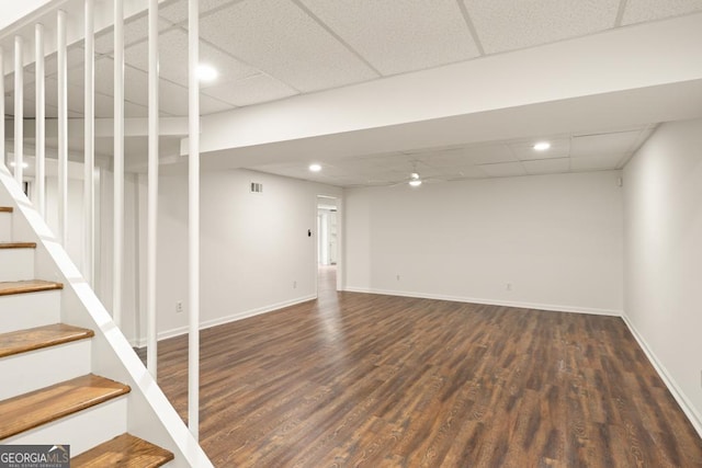 basement with a paneled ceiling and dark hardwood / wood-style flooring