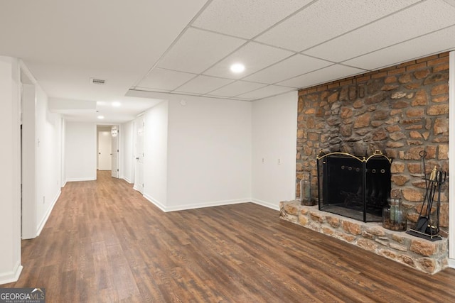 unfurnished living room featuring a fireplace, a drop ceiling, and hardwood / wood-style flooring