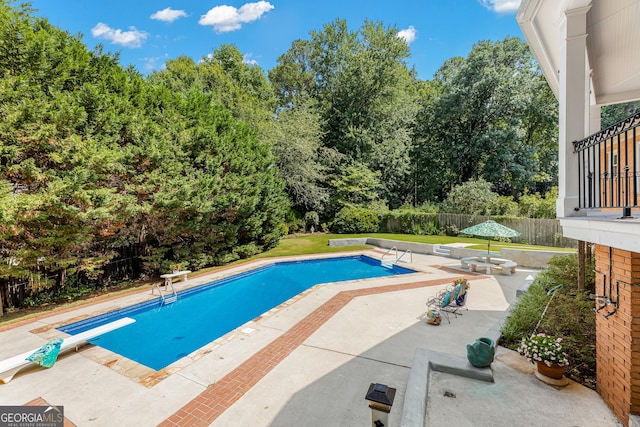 view of pool featuring a patio area, a diving board, and a yard