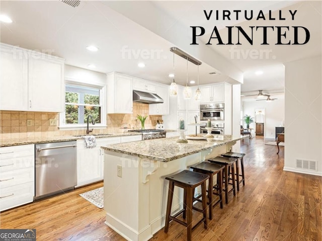 kitchen with white cabinetry, a center island, decorative light fixtures, and appliances with stainless steel finishes