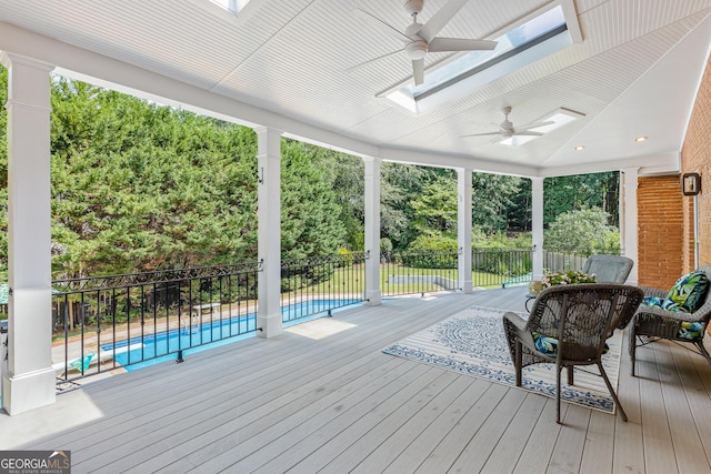 wooden terrace with a fenced in pool and ceiling fan