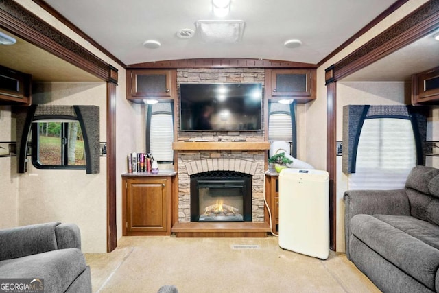 carpeted living room with a stone fireplace, lofted ceiling, and ornamental molding