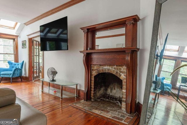 living area featuring ornamental molding, a fireplace, wood-type flooring, and a skylight