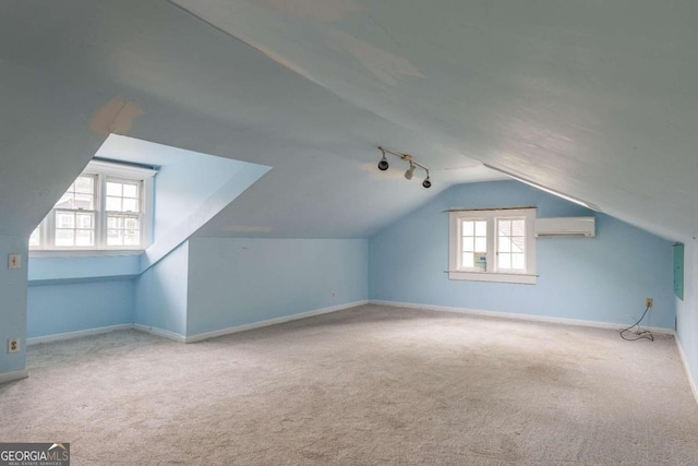 additional living space with carpet flooring, plenty of natural light, lofted ceiling, and an AC wall unit