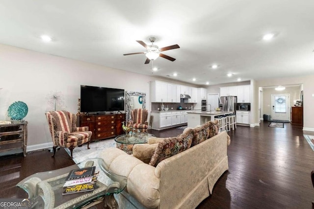 living room featuring ceiling fan, sink, and dark hardwood / wood-style flooring