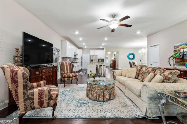 living room with ceiling fan with notable chandelier and dark hardwood / wood-style flooring