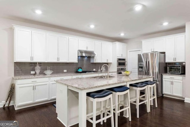 kitchen featuring stainless steel appliances, dark hardwood / wood-style floors, sink, an island with sink, and white cabinets