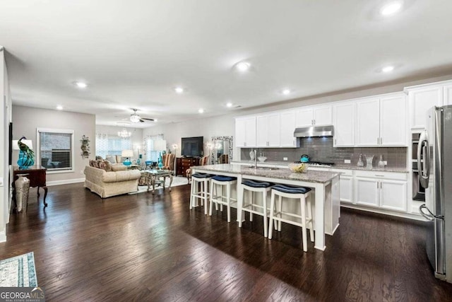 kitchen featuring white cabinetry, a kitchen breakfast bar, dark hardwood / wood-style floors, and a kitchen island with sink