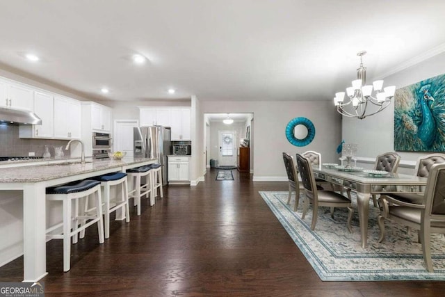 dining room featuring ornamental molding, a notable chandelier, dark hardwood / wood-style floors, and sink