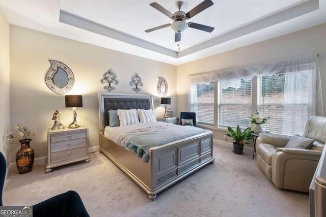 carpeted bedroom featuring ceiling fan and a raised ceiling