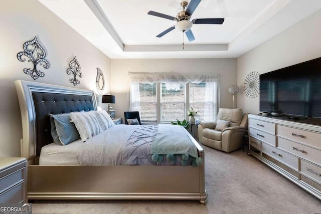 bedroom featuring light carpet, ceiling fan, and a raised ceiling