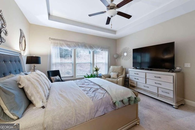 carpeted bedroom featuring ceiling fan and a raised ceiling