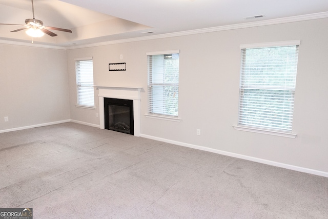 unfurnished living room with ceiling fan, ornamental molding, and light colored carpet