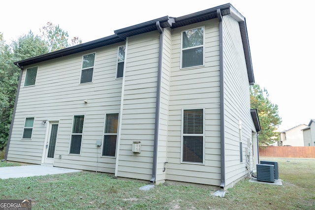 rear view of property featuring central AC unit and a yard