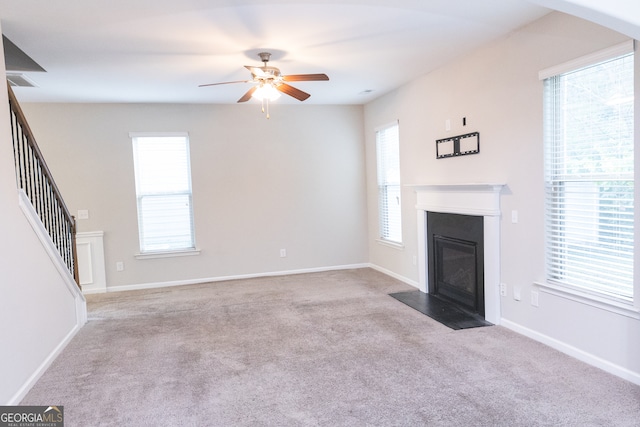 unfurnished living room featuring light colored carpet and ceiling fan