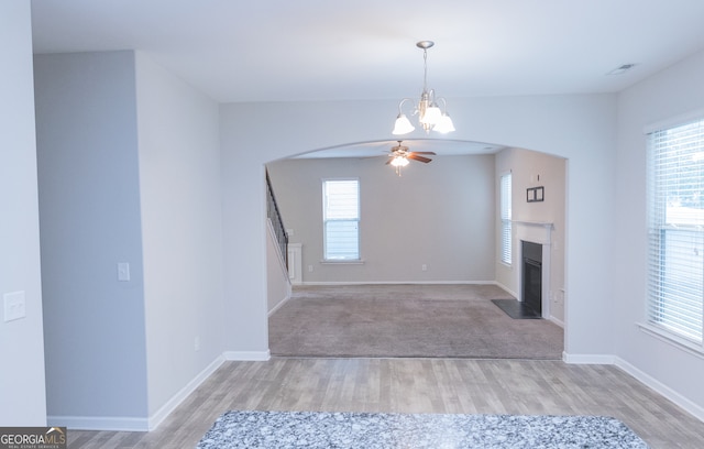 unfurnished living room featuring light hardwood / wood-style floors and ceiling fan with notable chandelier