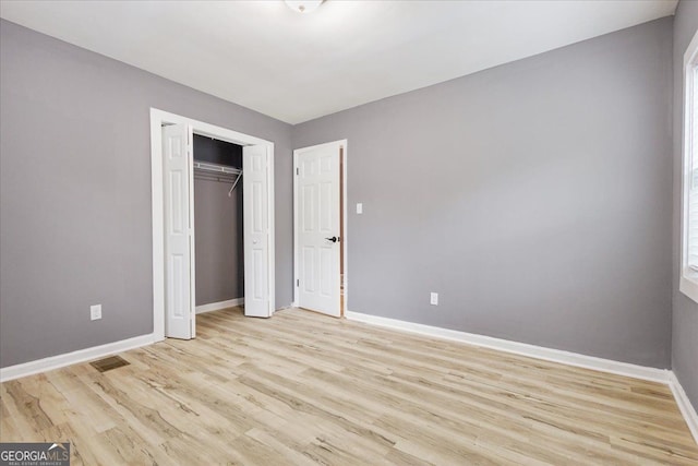 unfurnished bedroom with a closet and light wood-type flooring