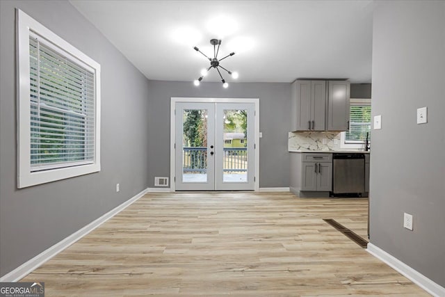 kitchen featuring stainless steel dishwasher, a chandelier, light hardwood / wood-style flooring, gray cabinetry, and french doors