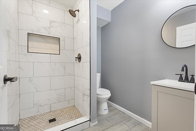 bathroom with vanity, toilet, and a tile shower