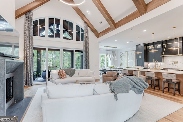 living room with high vaulted ceiling, sink, beamed ceiling, and hardwood / wood-style floors