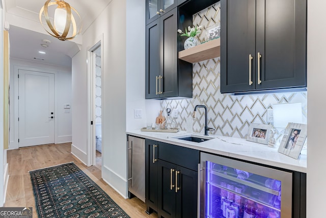 bar featuring beverage cooler, sink, light hardwood / wood-style flooring, and light stone counters