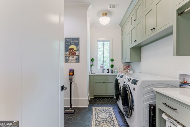 laundry room featuring dark tile patterned floors, cabinets, sink, and washer and dryer