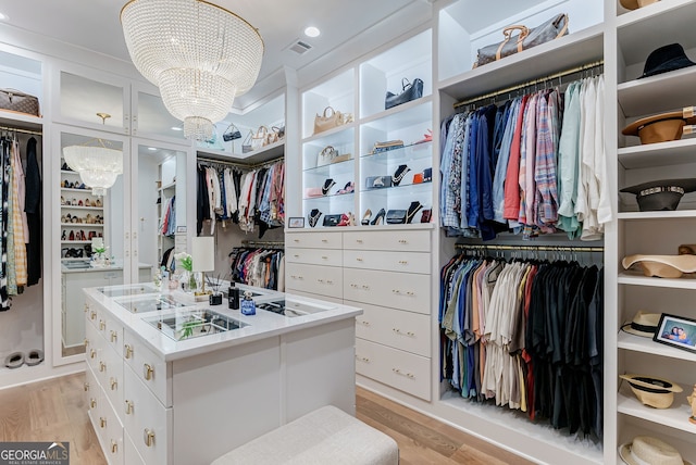 walk in closet featuring a notable chandelier and light hardwood / wood-style floors