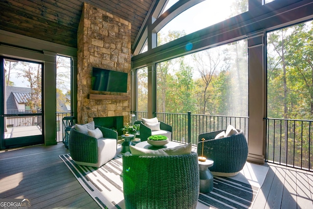 sunroom featuring vaulted ceiling, wooden ceiling, and a fireplace